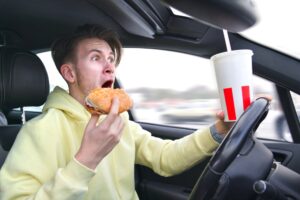 man eating and drinking while driving