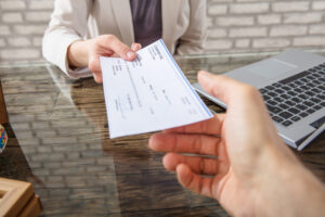 A person hands a settlement check to an injured motorist after a rear-end collision claim is resolved.