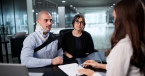 An injured motorcycle rider and a family member meet with an injury attorney to discuss a settlement related to a motorcycle accident claim.