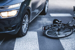 A damaged bicycle sits near a car at the scene of a hit and run accident. A hit and run accident can leave an injured person seeking other ways to recover damages when the driver cannot be found.